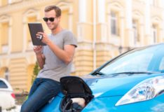 Man reclining on his electric car eigenheim umweltbonus